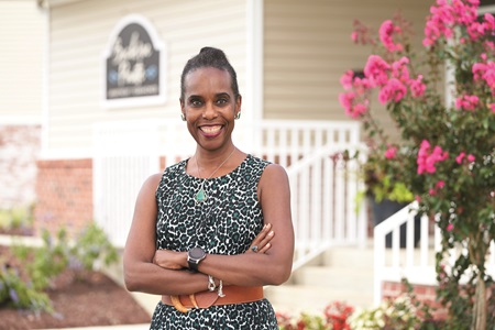 Faith Linton, Real Estate Devloper in front of flowers and building
